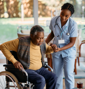 nurse assists senior man to get up from wheelchair