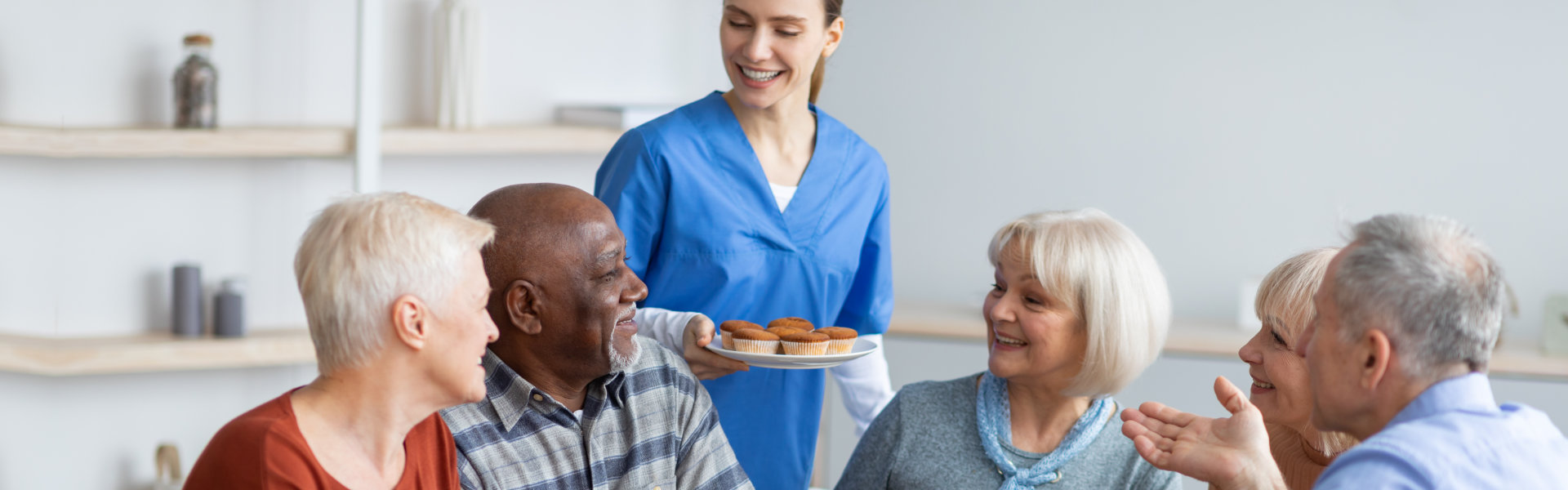 nurse holding plate with cupcakes giving it to the elderly people