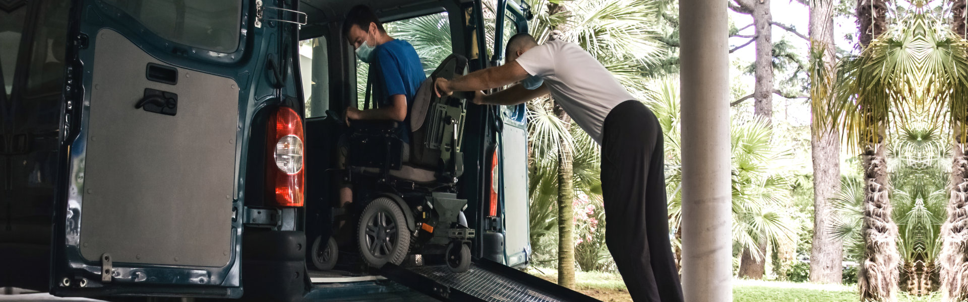 Assistant helping man on wheelchair getting down on ramp